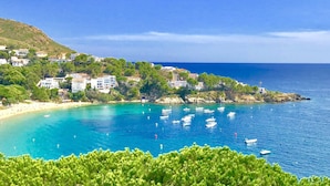 Un pueblo costero con edificios en una colina que domina un mar azul cristalino.