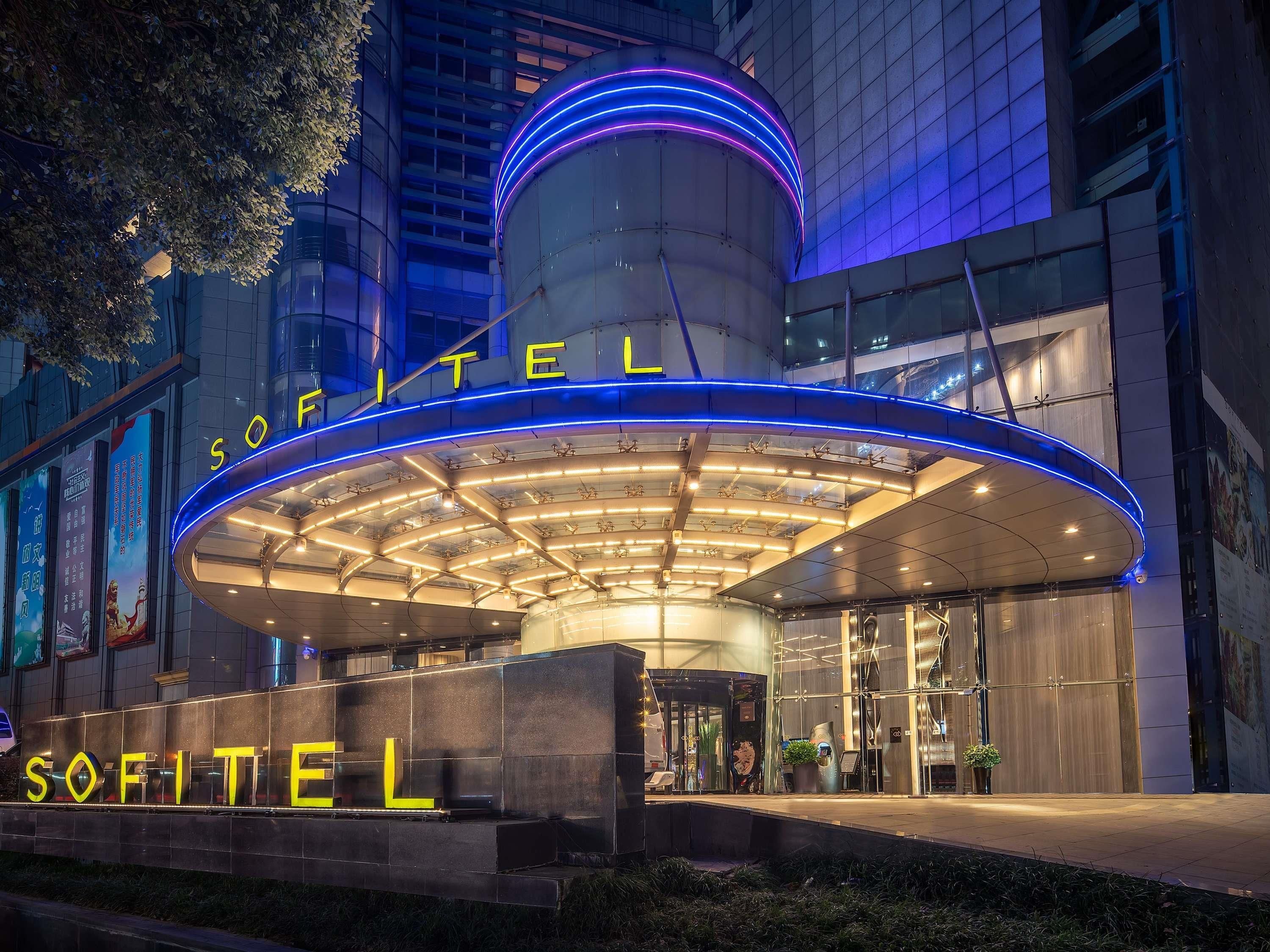 A hotel entrance with a modern design, featuring a prominent circular structure and illuminated signage.