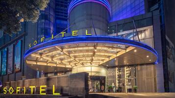 A hotel entrance with a modern design, featuring a prominent circular structure and illuminated signage.