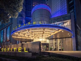 A hotel entrance with a modern design, featuring a prominent circular structure and illuminated signage.
