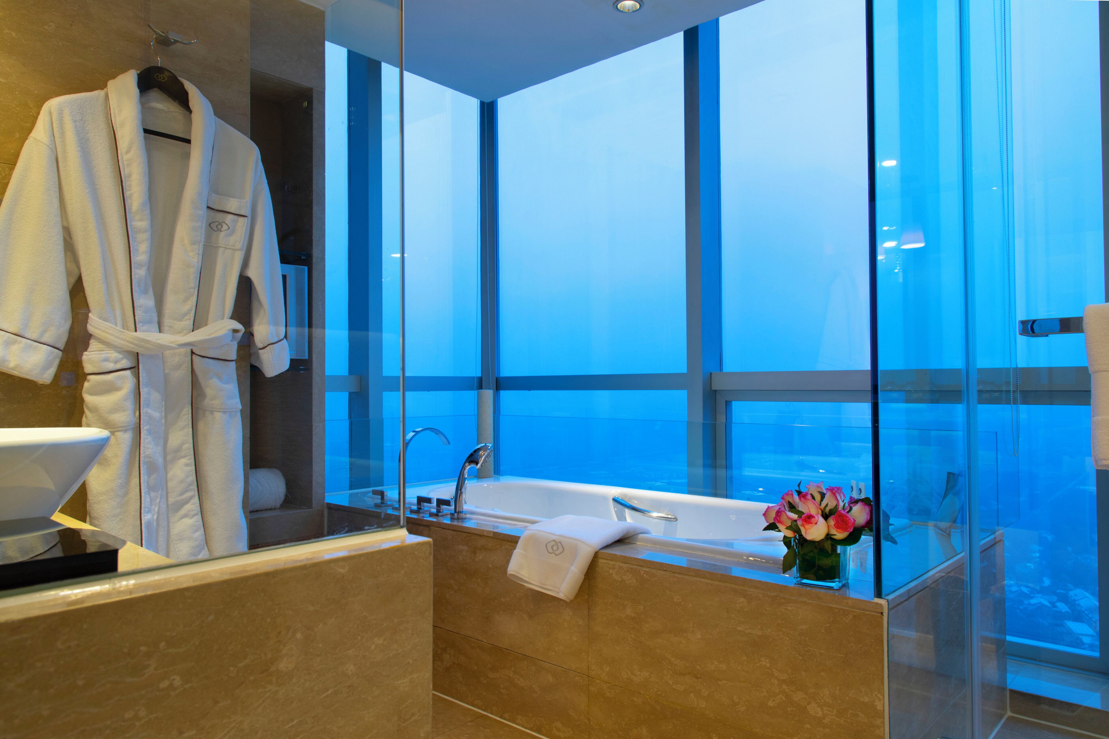 Un baño moderno con una bañera grande, una ducha con mampara de vidrio y vistas al cielo.