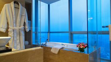 Un baño moderno con una bañera grande, una ducha con mampara de vidrio y vistas al cielo.