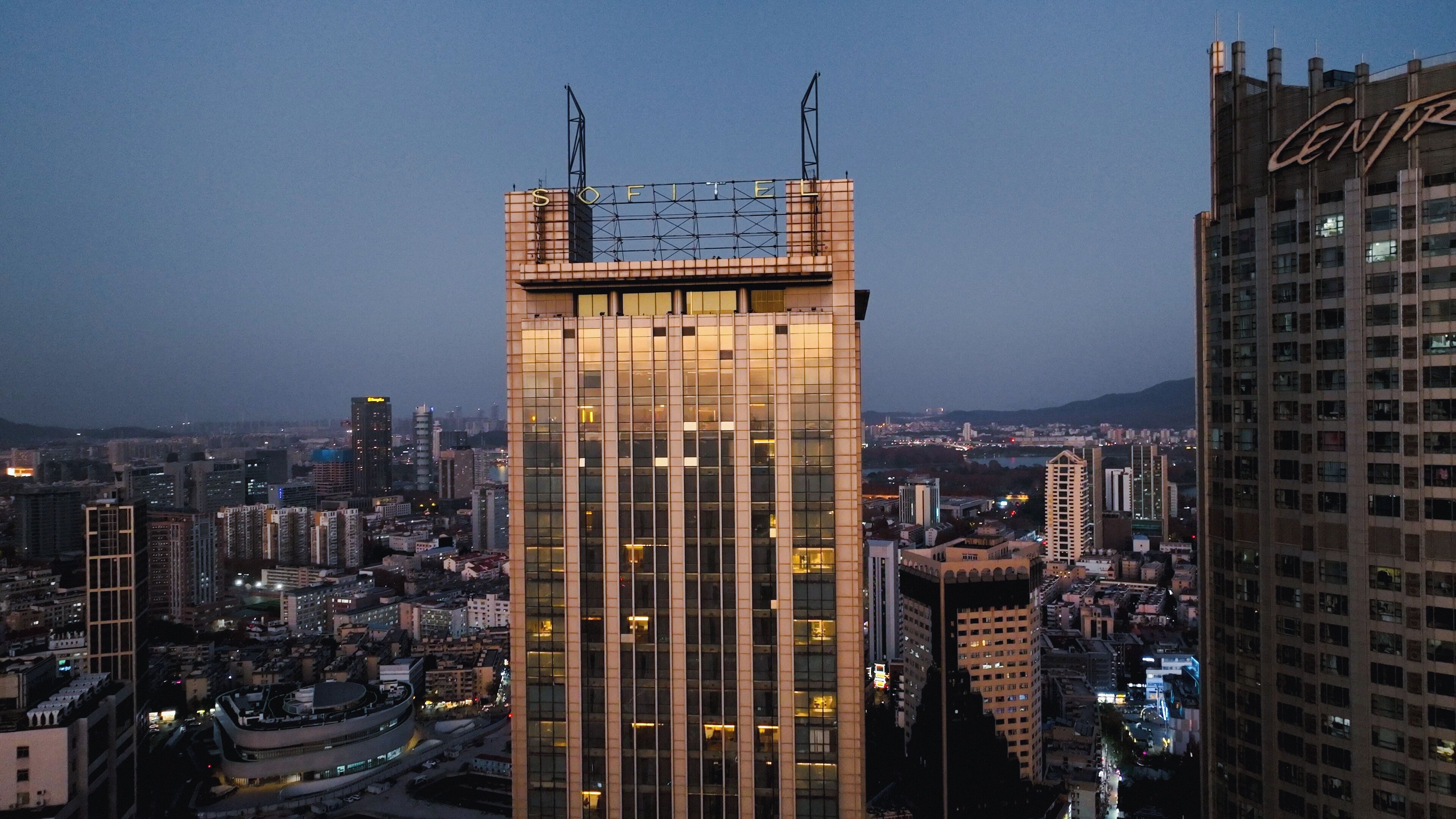 A high-rise building with a grid-like facade and a prominent sign at the top.