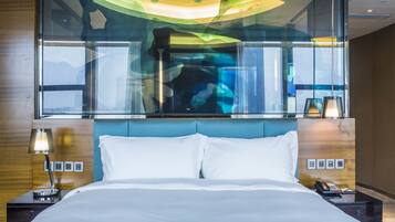 A hotel room with a large bed, a nightstand with a lamp, a phone, and a wall-mounted picture.