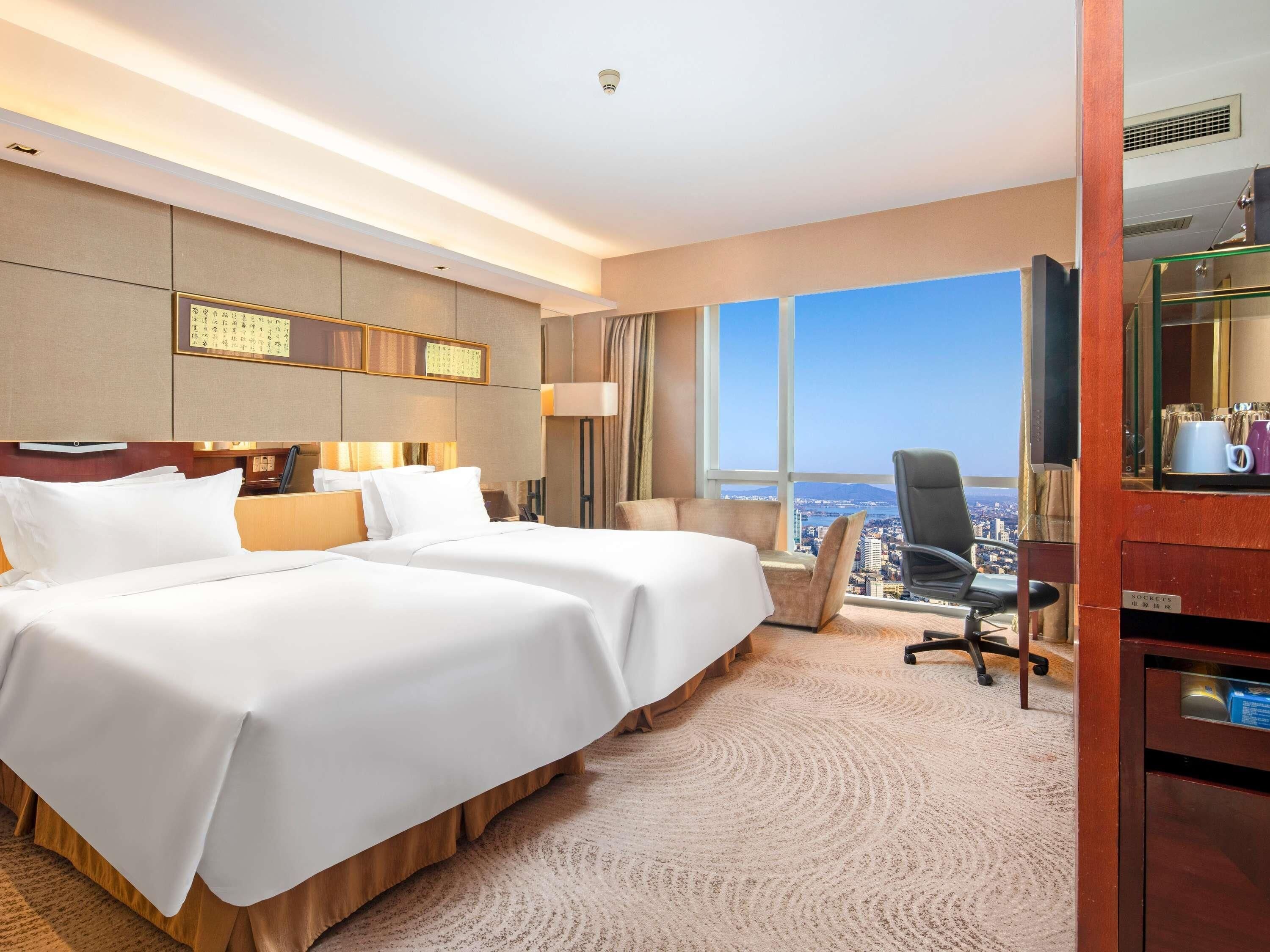 Een hotelkamer met een groot bed, een bureau, een stoel en uitzicht op de stad.