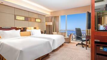Een hotelkamer met een groot bed, een bureau, een stoel en uitzicht op de stad.