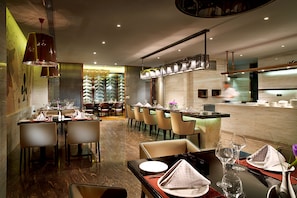 Un interior de restaurante moderno con mesas altas, sillas y una zona de bar.