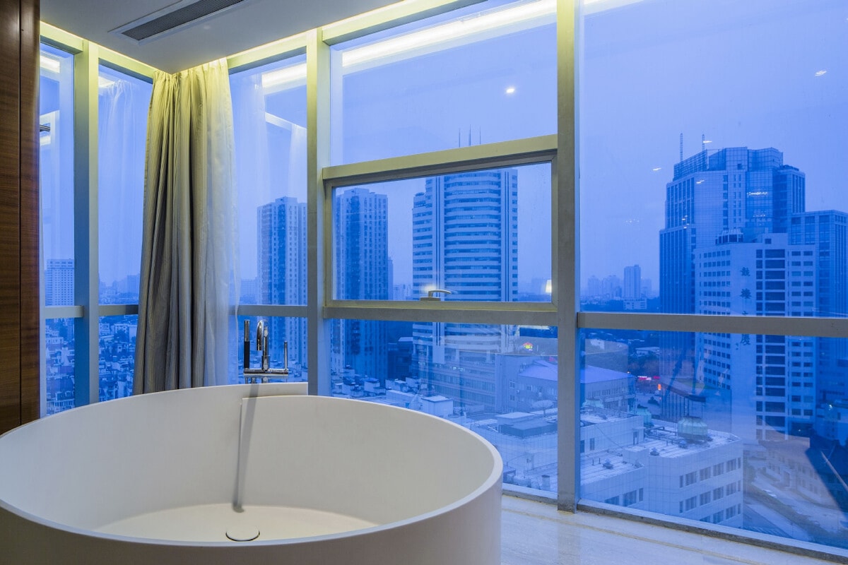Un baño moderno con una bañera grande, ventanas amplias y vistas a la ciudad.