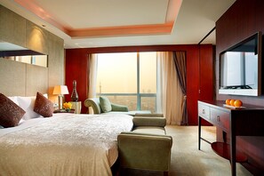 Relax in a spacious room with a large bed, seating area, and city views.