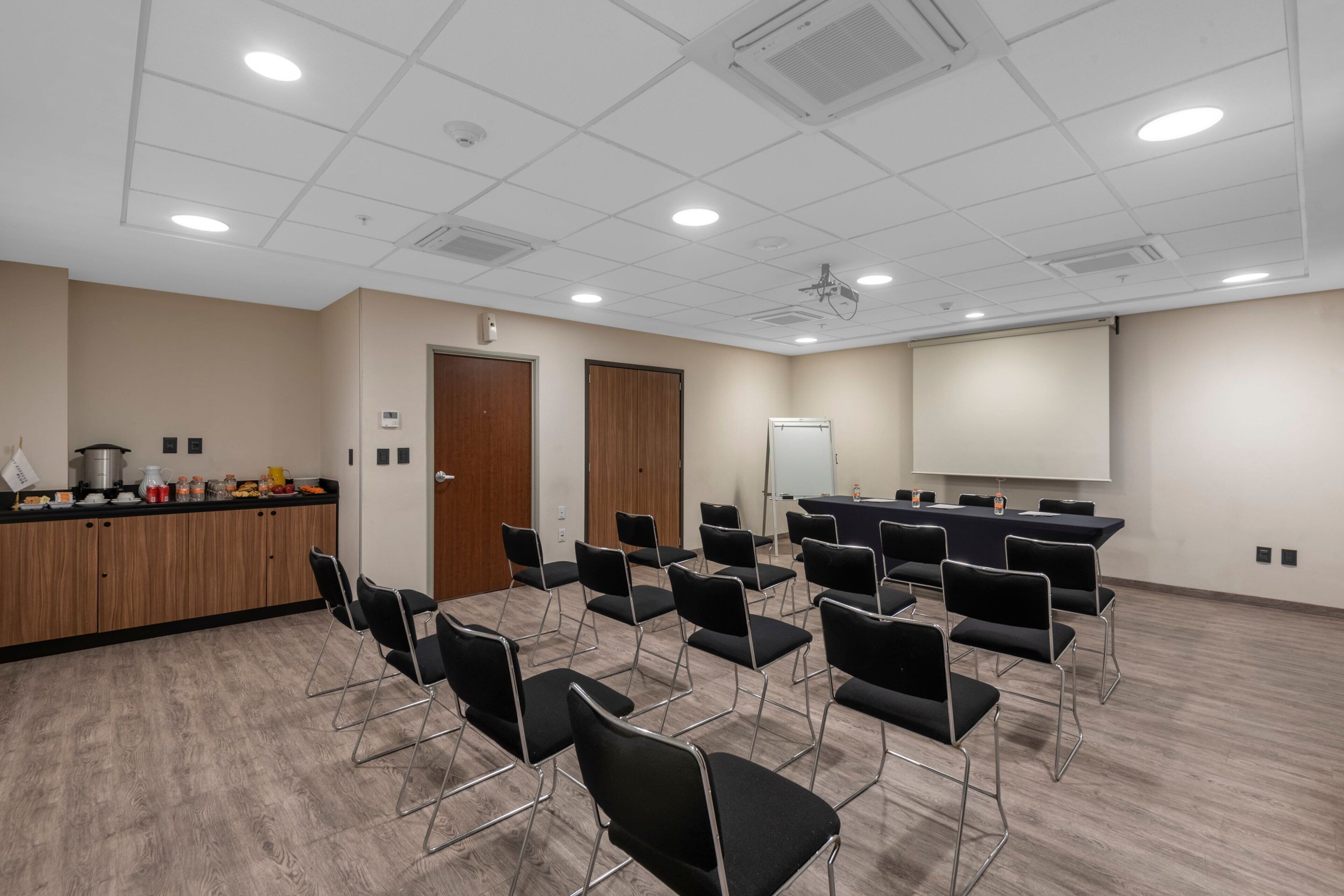 A conference room with a whiteboard, projector, and a long table with chairs.
