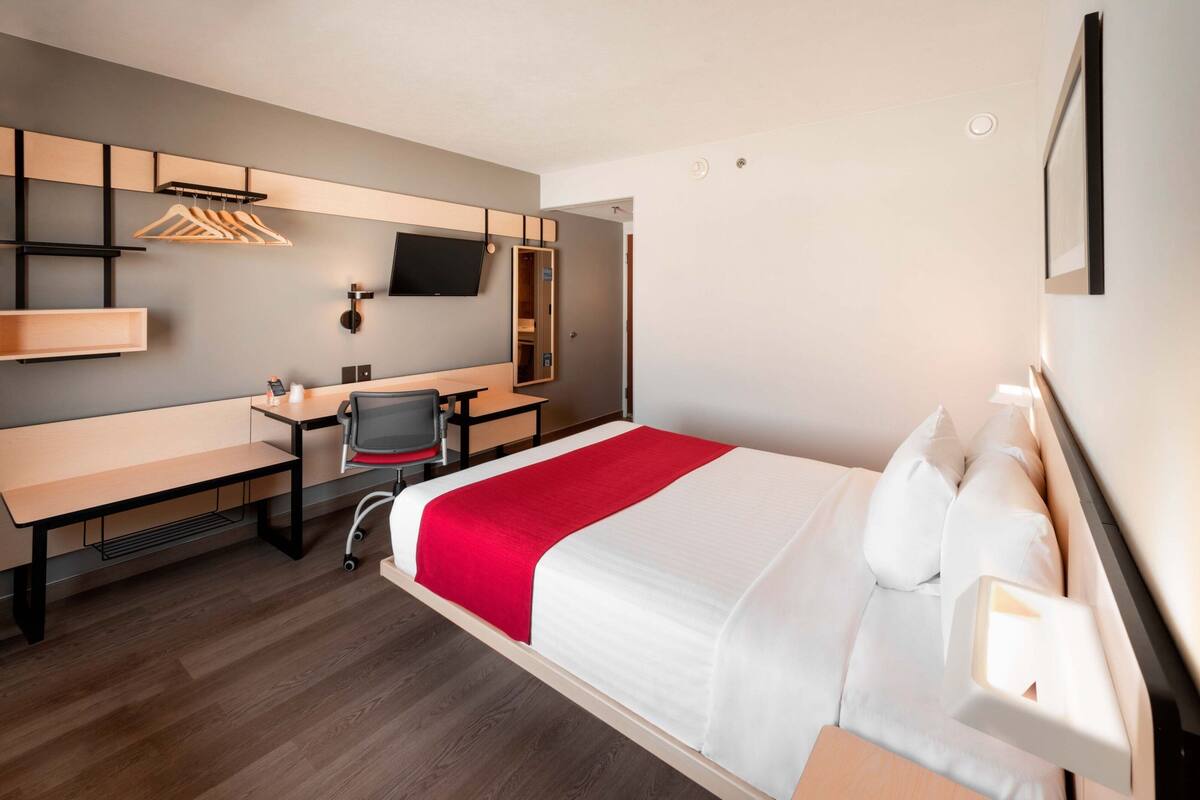 Une chambre d’hôtel équipée d’un lit, d’un bureau, d’une chaise, d’une télévision et d’une armoire.