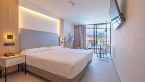 A modern hotel room with a large bed, a desk, and a balcony with a view of the city. - Hotel Merlin Resort (Adeje)