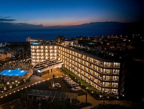 Un hotel con piscina, diversi piani e vista sul mare.