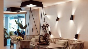 A modern interior with a sofa, chairs, a table, and pendant lighting. - Hotel Merlin Resort (Adeje)