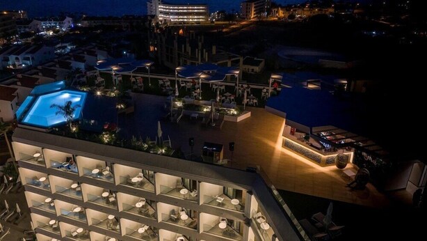 A hotel with a rooftop pool, outdoor seating, and a view of the sea. - Hotel Merlin Resort (Adeje)