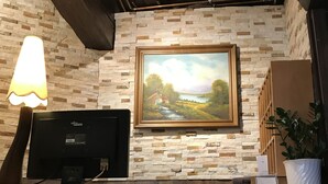 A reception desk with a flat-screen TV, a lamp, a framed painting, and a potted plant. - Ritter Hotel (Frankfurt)