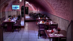 A restaurant with a cave-like interior, featuring a long communal table and individual tables with chairs. - Ritter Hotel (Frankfurt)