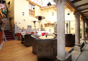 Un espacio interior acogedor con columnas de piedra, suelo de madera y pared amarilla.