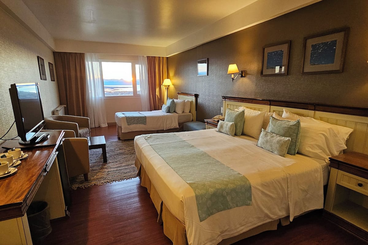 Camera d'albergo con due letti, una scrivania con un computer, una TV e vista sull'esterno.