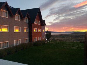 Un edificio moderno con múltiples ventanas y vistas a la puesta de sol sobre el agua.