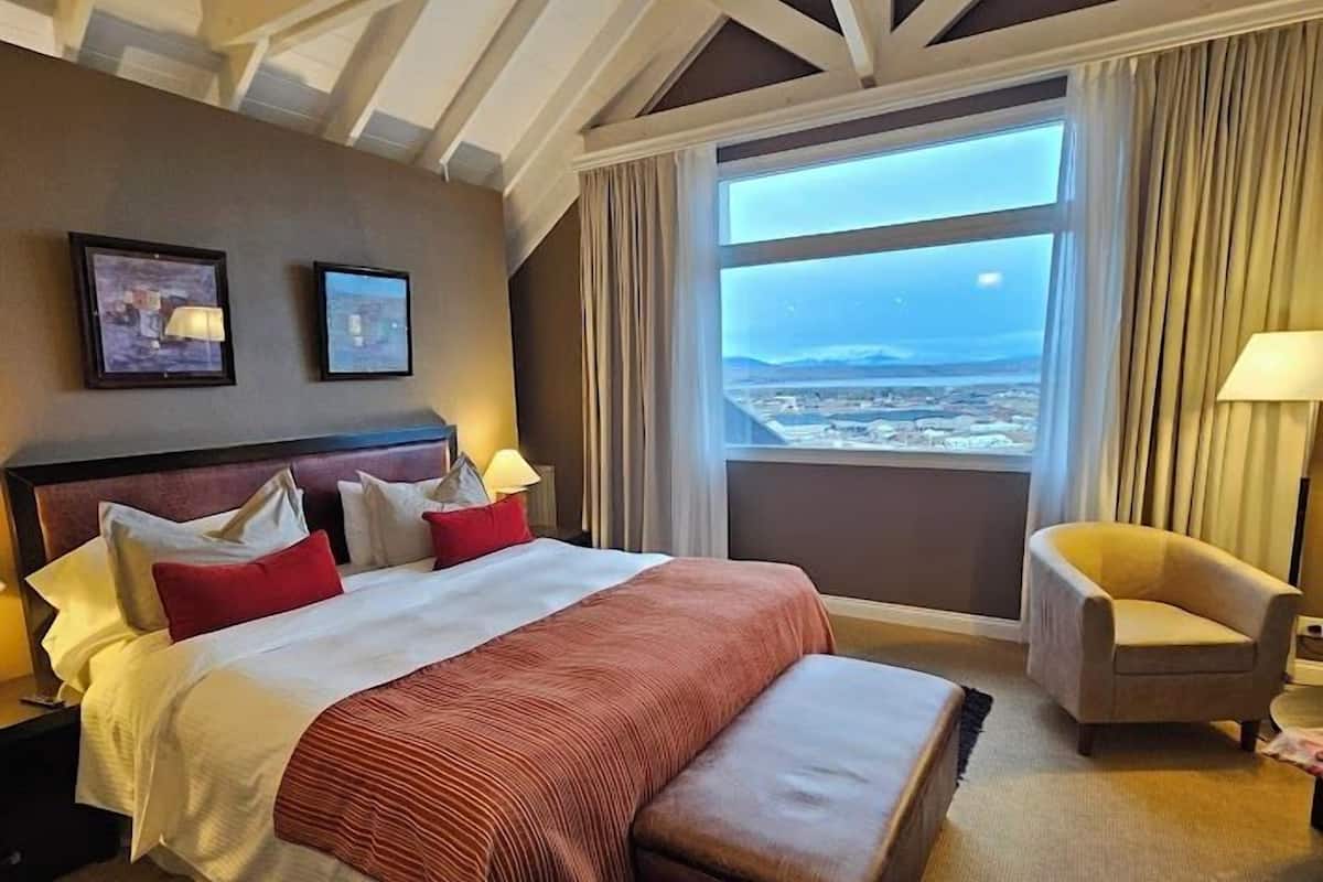 Camera d'albergo con un letto grande, vista sulla città e un design moderno del soffitto.