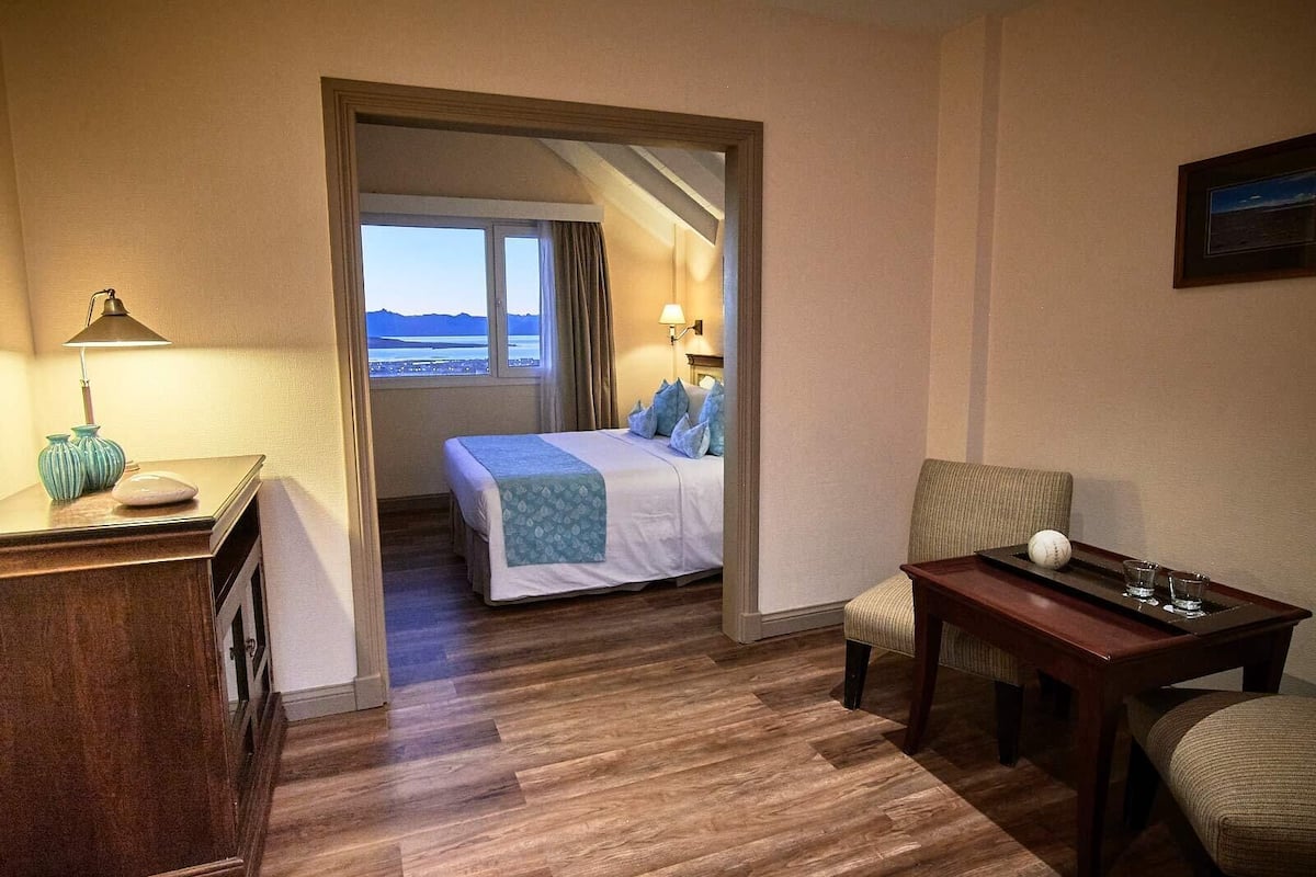 Una camera d'albergo con un letto, una scrivania, una sedia e vista mare dalla finestra.
