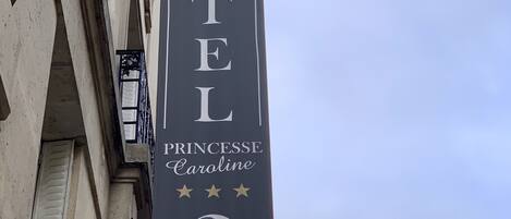 Un letrero de hotel con el nombre "HOTEL PRINCESSE Caroline" y un retrato de una mujer.