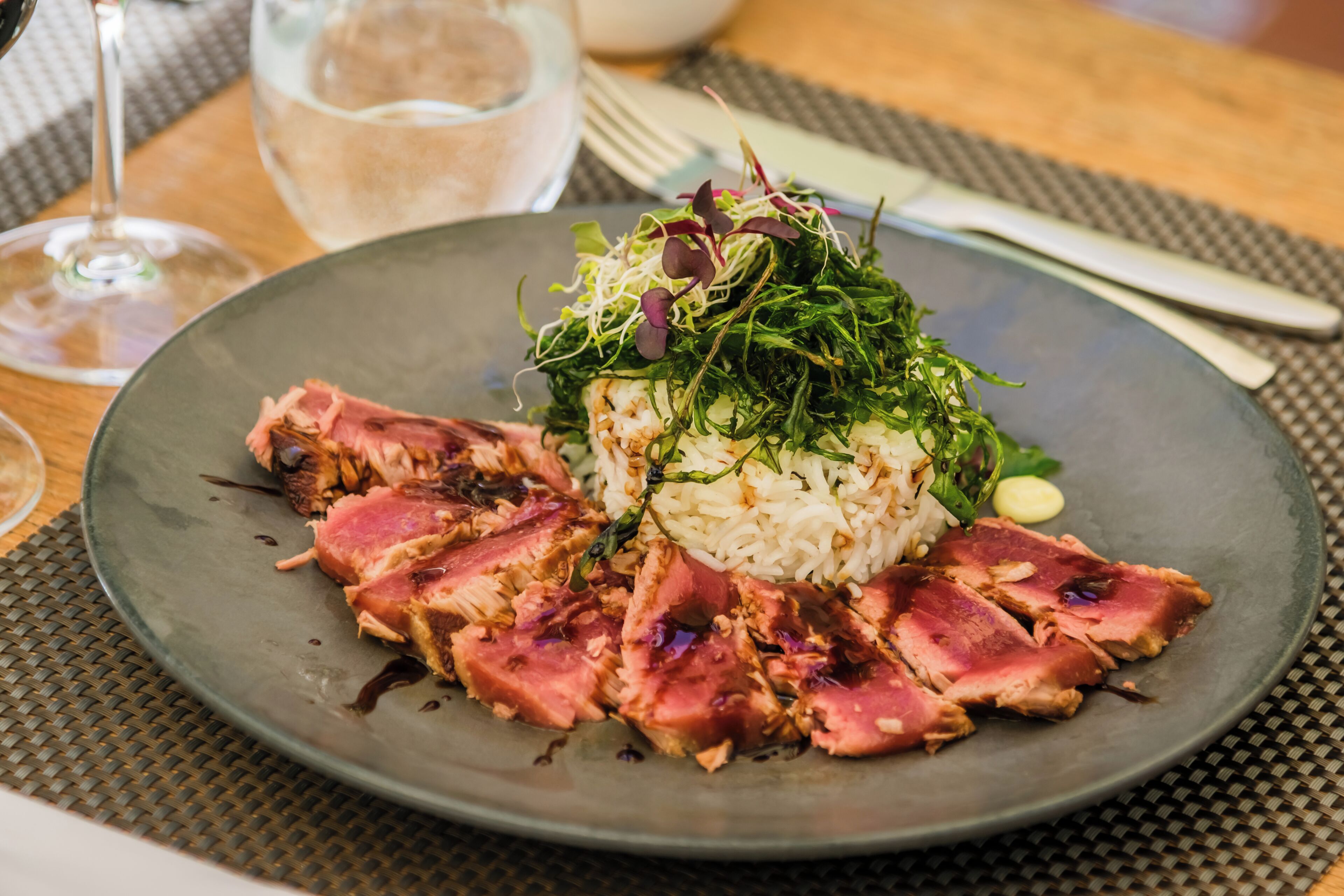 Un plato de comida con carne en rodajas, arroz y verduras sobre un plato oscuro.