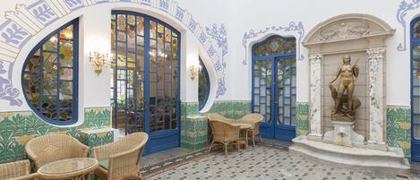 A courtyard with wicker furniture, blue doors, and a statue.
