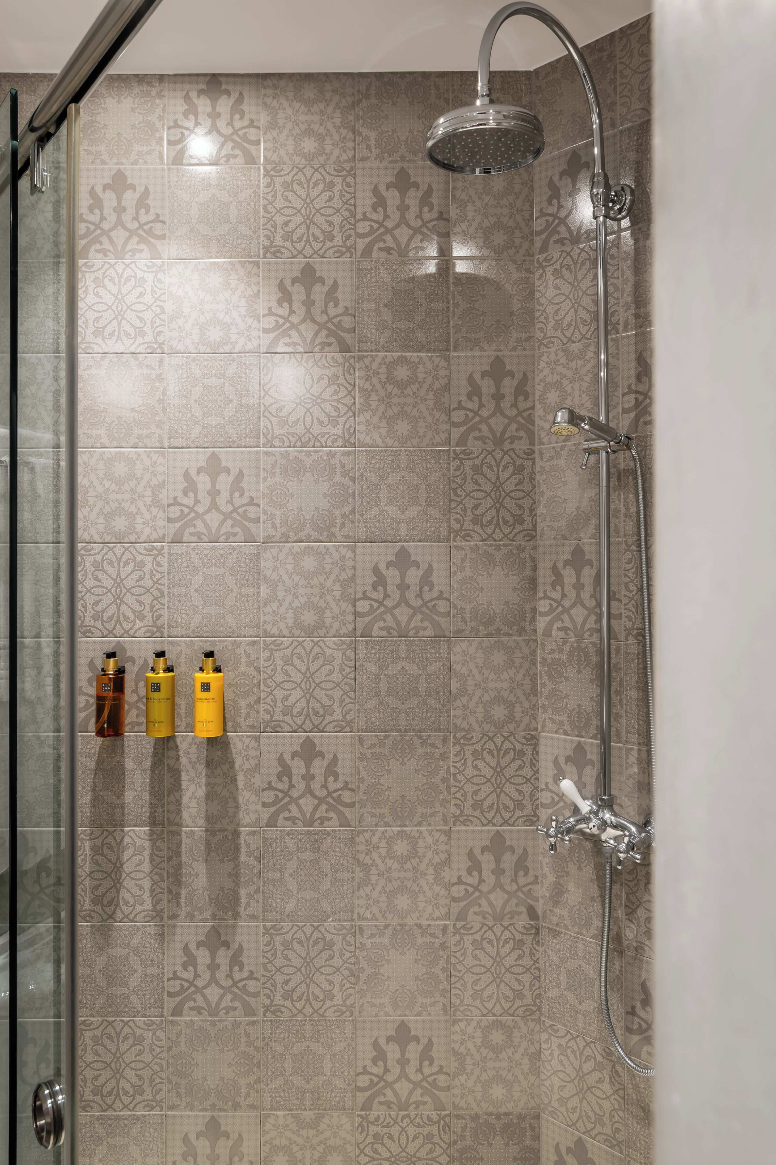 Une douche équipée d’un pommeau de douche à main et d’un robinet fixé au mur.
