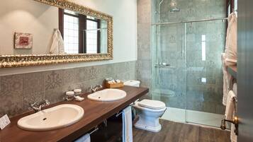 Une salle de bain avec deux lavabos, des toilettes et une douche à parois de verre.