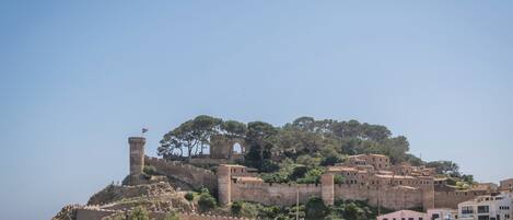 A coastal fortification with a tower, surrounded by buildings and vegetation.