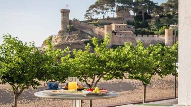 Una mesa con alimentos para el desayuno y vistas a un castillo histórico.