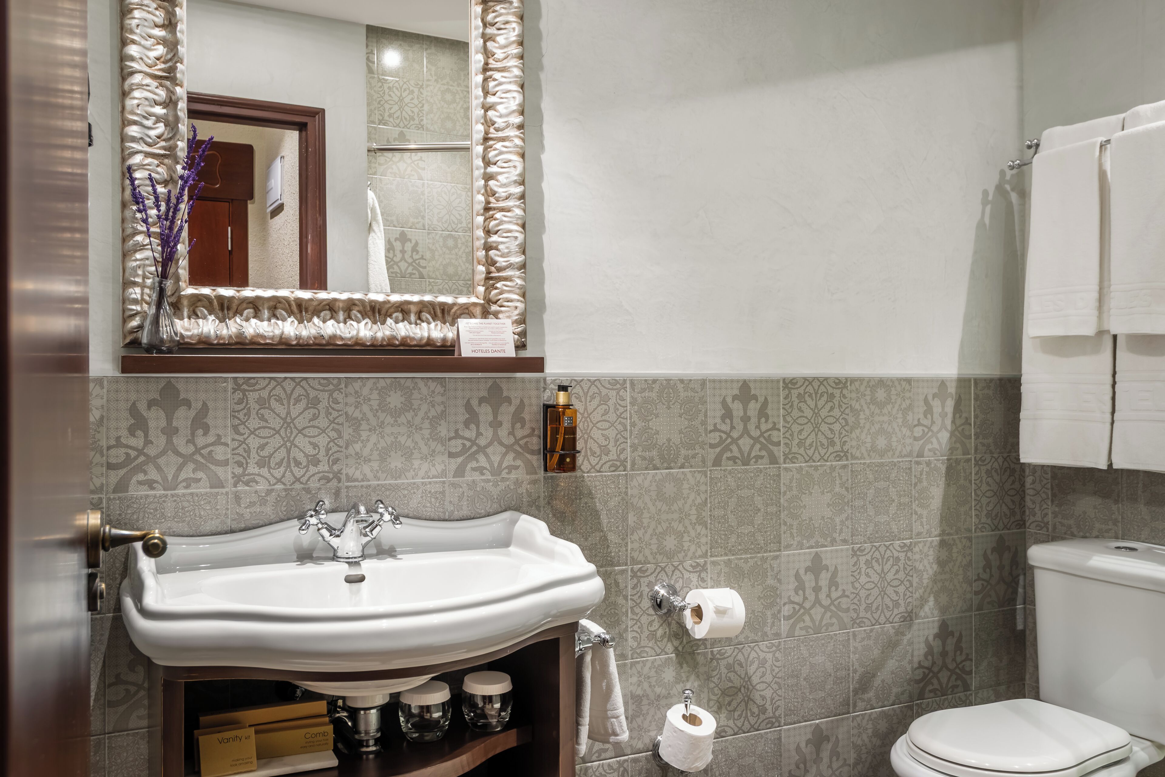 Ein Badezimmer mit Waschbecken, Spiegel, Toilette und gemusterten Fliesen.