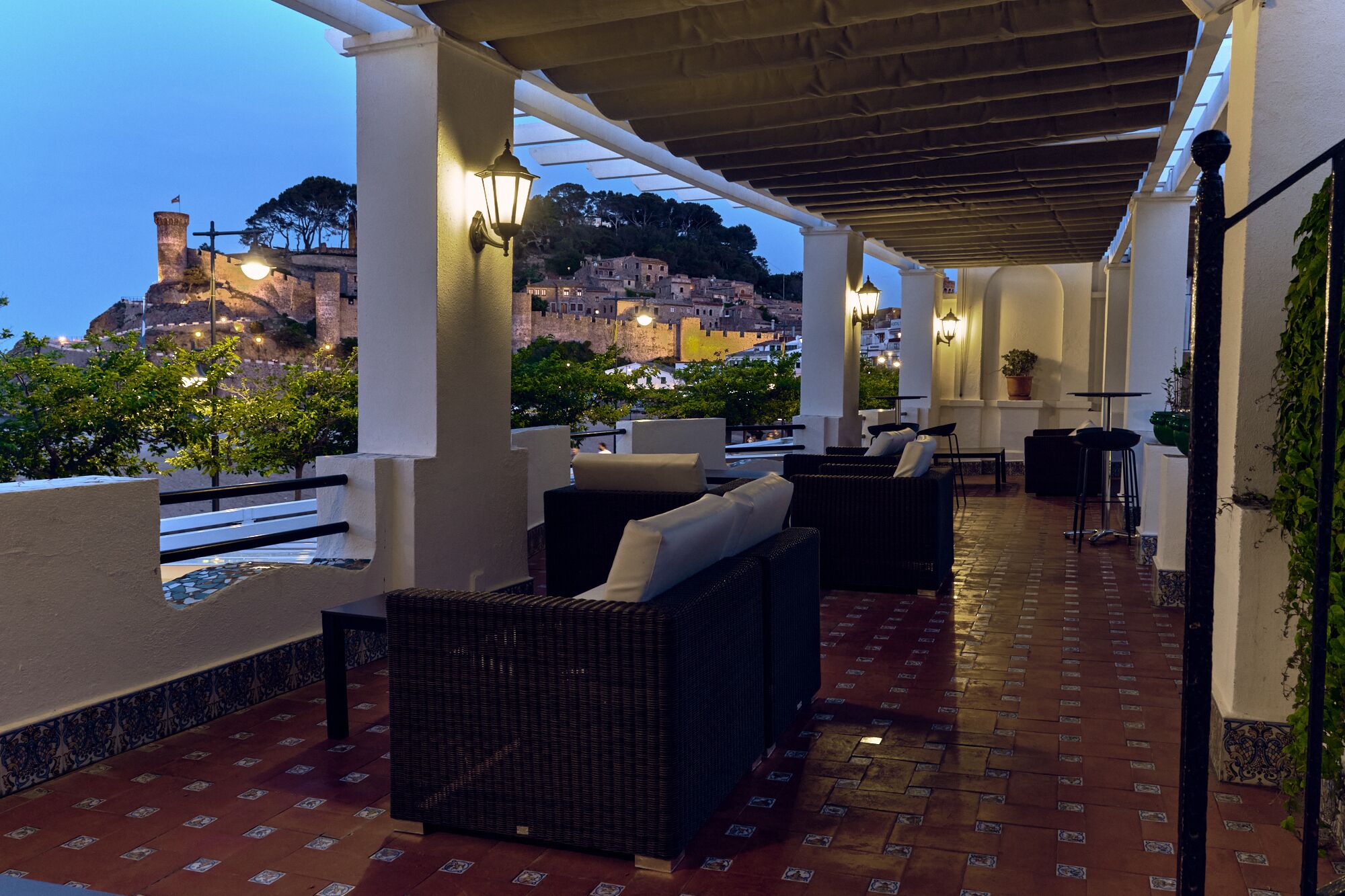 An outdoor patio with wicker furniture, a tiled floor, and a view of a historic fort.