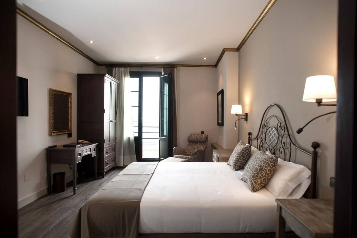 Una habitación de hotel con una cama grande, un escritorio con teléfono, una silla y una lámpara.