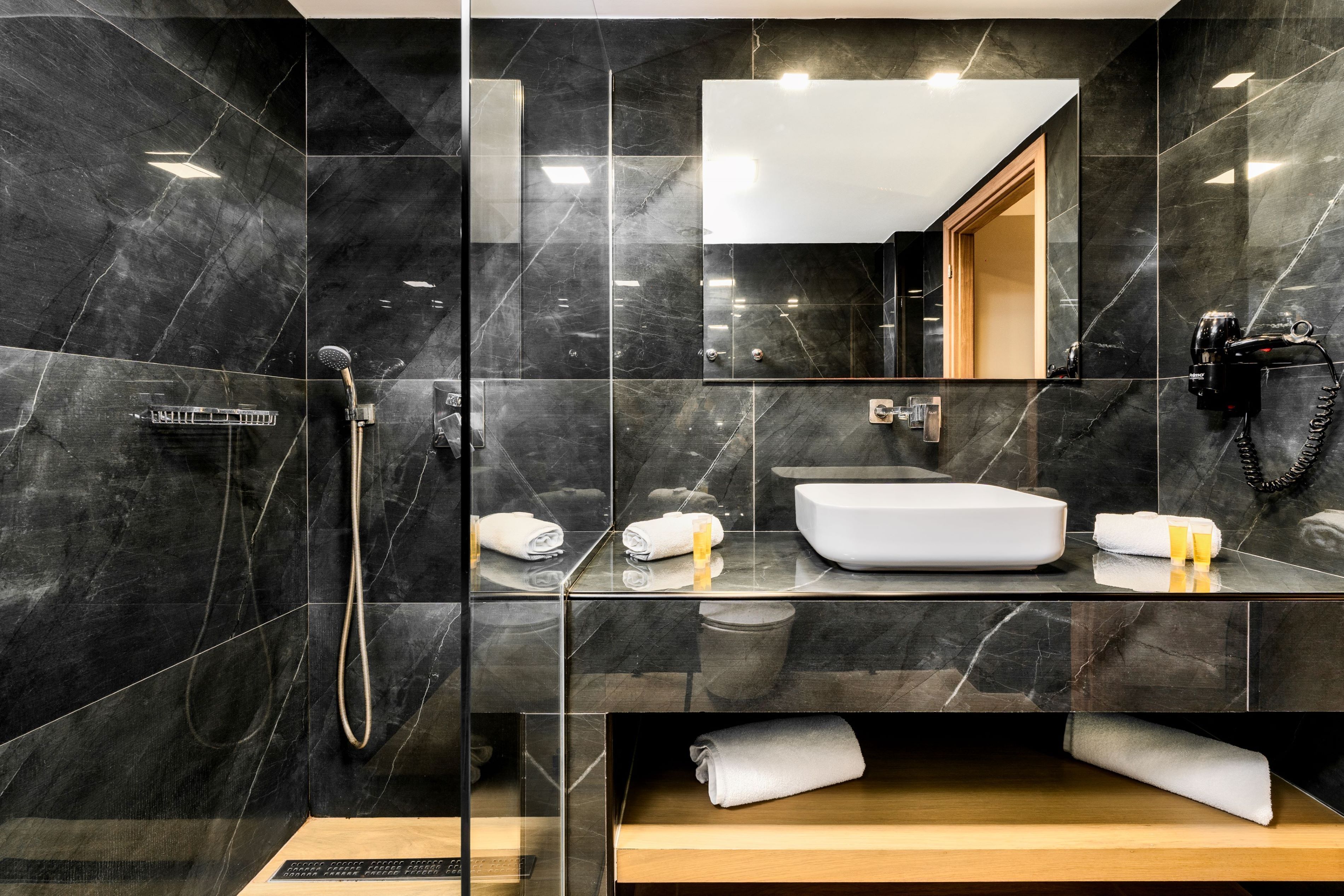 Een moderne badkamer met een grote spiegel, een wastafel en een douche.