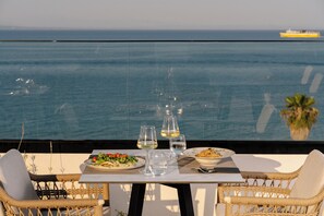 A dining table with plates of food, glasses, and a view of the ocean. - Palatino Hotel (Zakynthos)