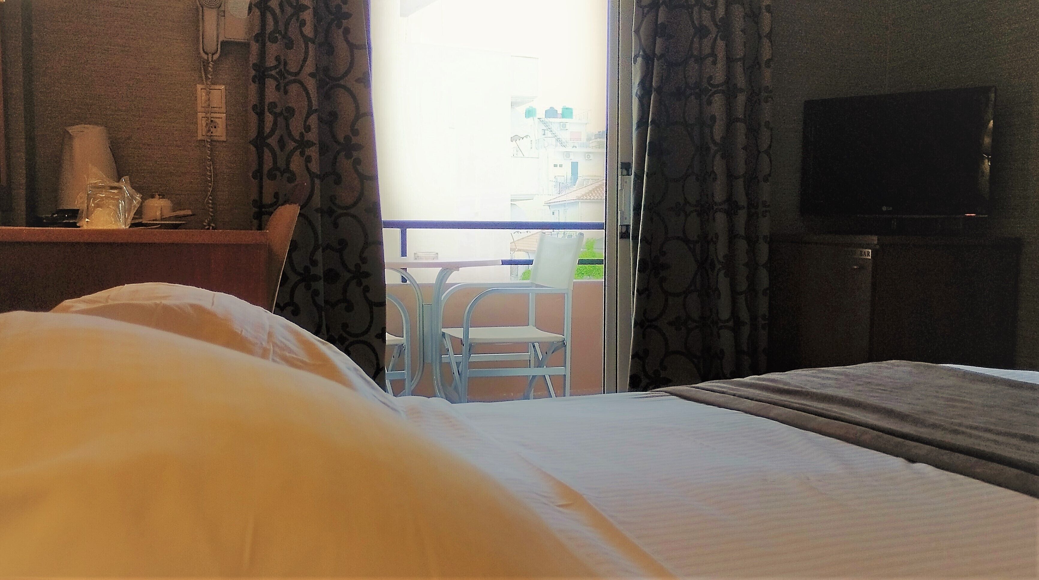 Una habitación de hotel con una cama, un televisor, una mesita y una silla.