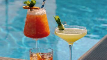 Dos bebidas sobre una mesa junto a la piscina, con una piscina al fondo.