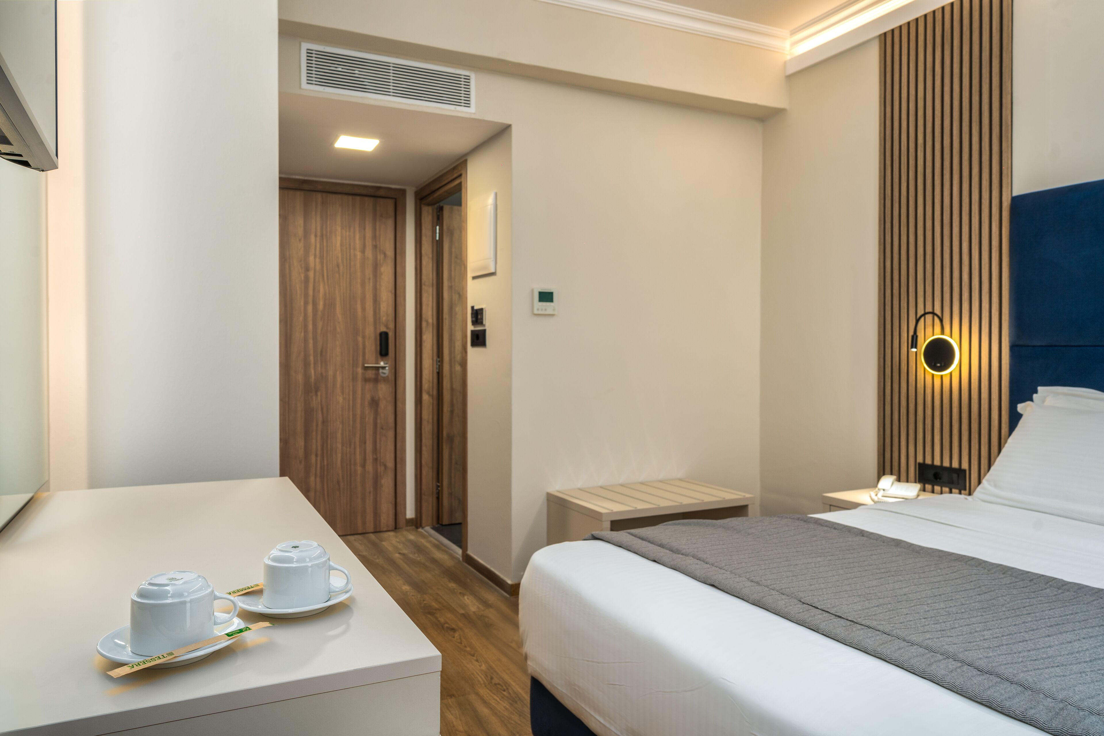 Ein Hotelzimmer mit einem Bett, einem Nachttisch und einem kleinen Tisch mit Tassen und einem Tablett.