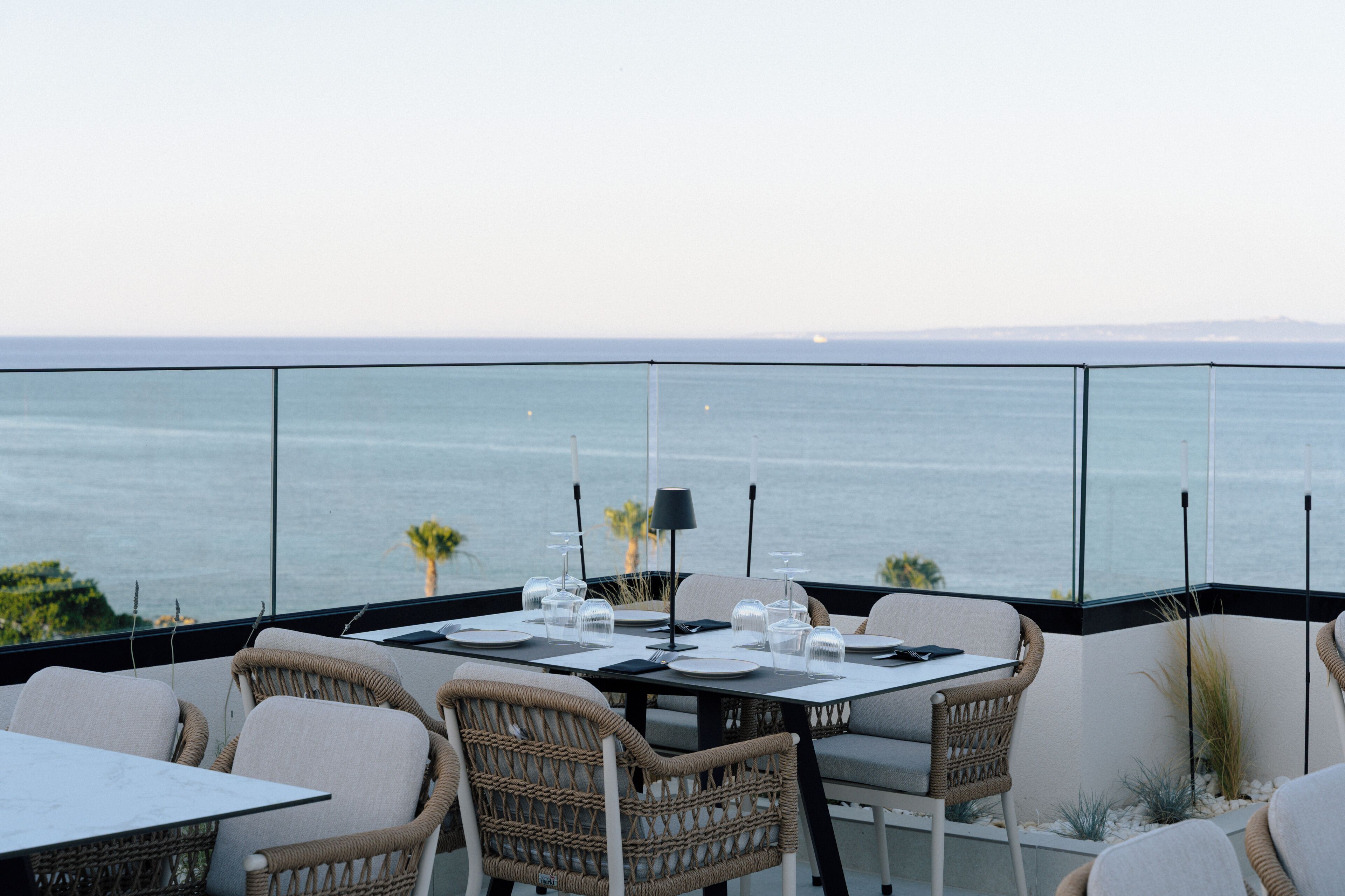 Comedor con mesas y sillas, con vista a un cuerpo de agua.