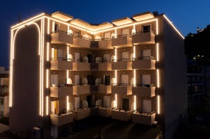 Un hotel a più piani con balconi, un cortile interno e illuminazione esterna.