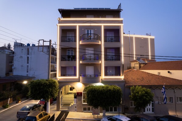 Un edificio de varios pisos con balcones, una escalera y una bandera.