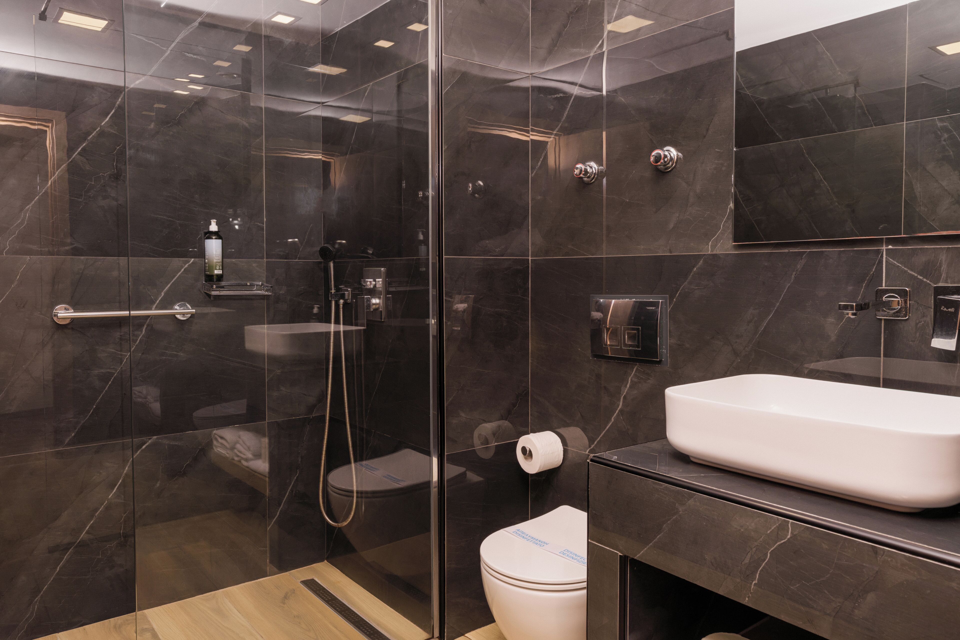 Ein modernes Badezimmer mit einer gläsernen Dusche, einem weißen Waschbecken und einer Toilette.