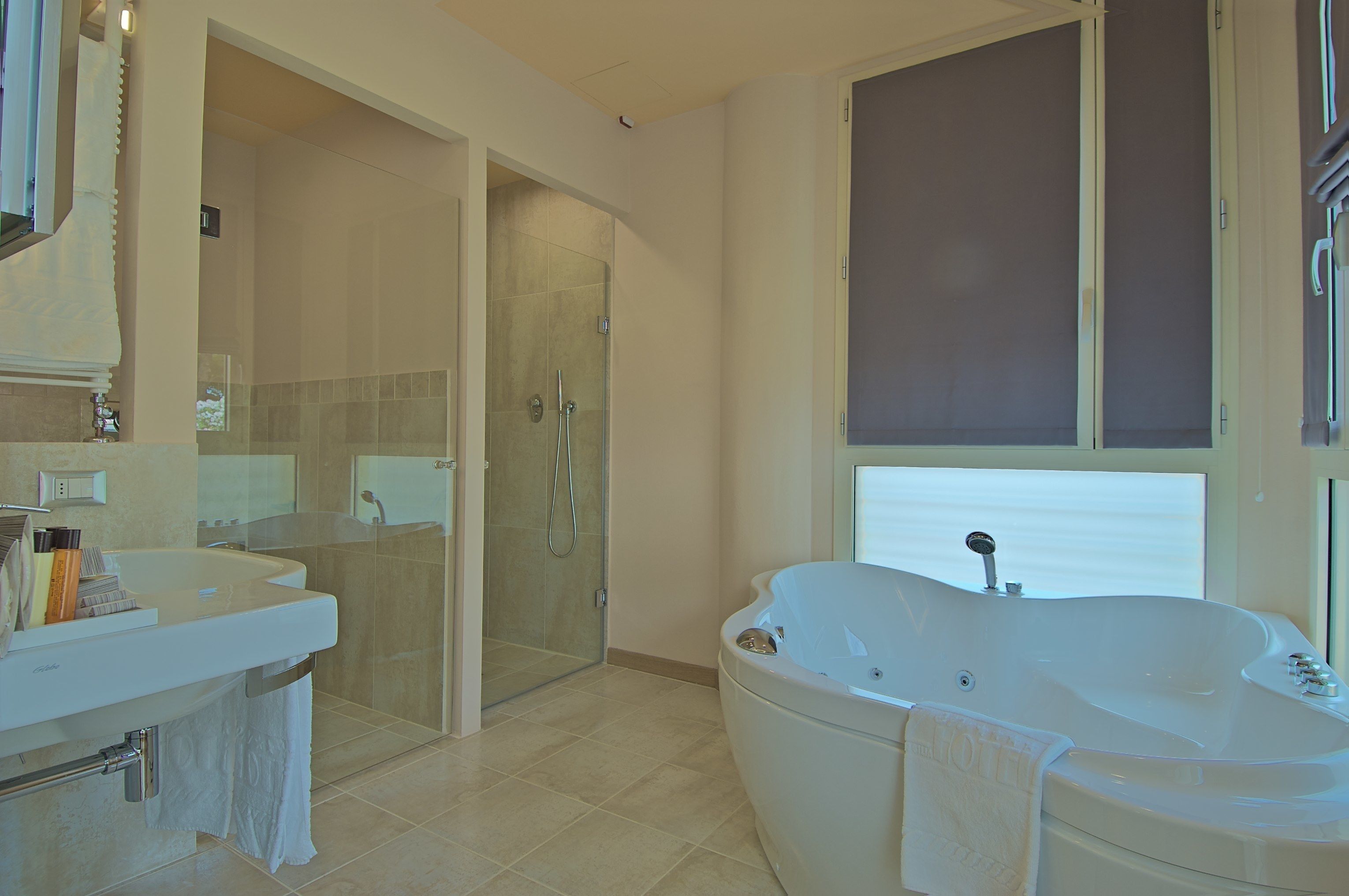 A modern bathroom with a large bathtub, a glass-enclosed shower, and a vanity with a sink and mirror.