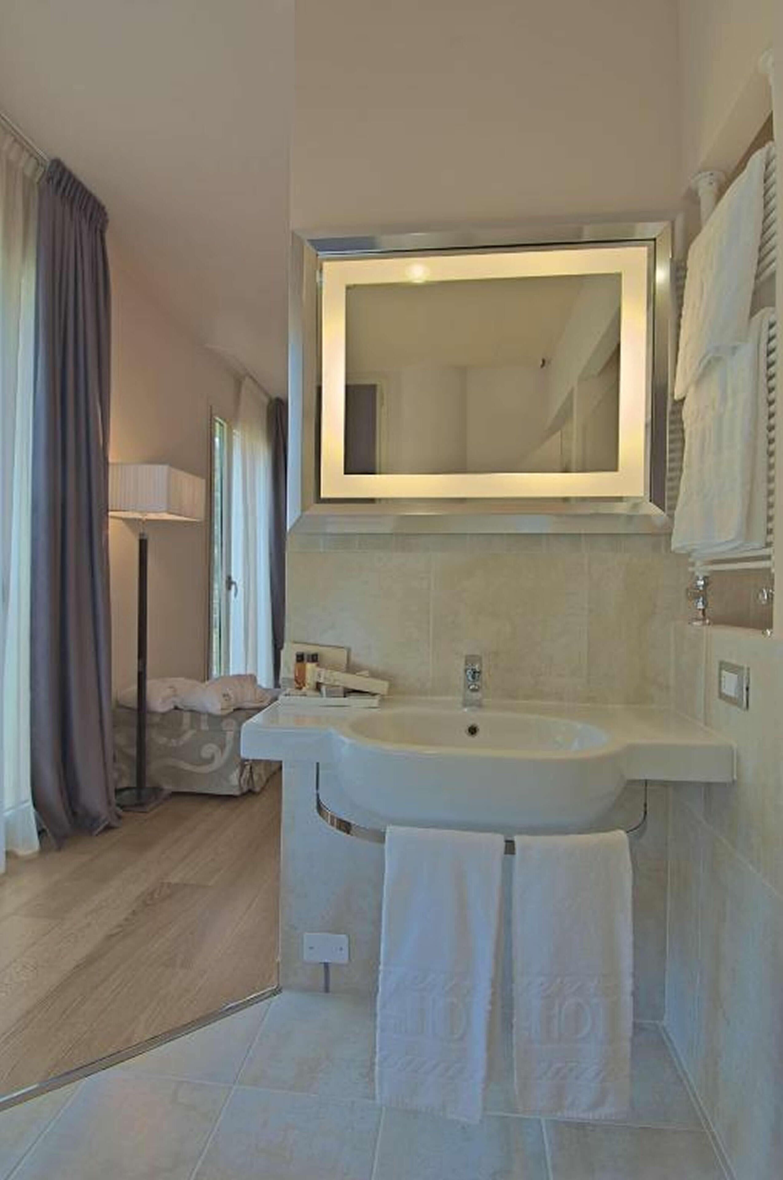 Une salle de bain moderne avec un grand miroir, un lavabo et un porte-serviettes.