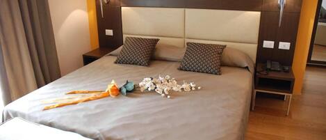 A neatly made bed with a headboard, two bedside tables with lamps, and a bedside table with a phone.