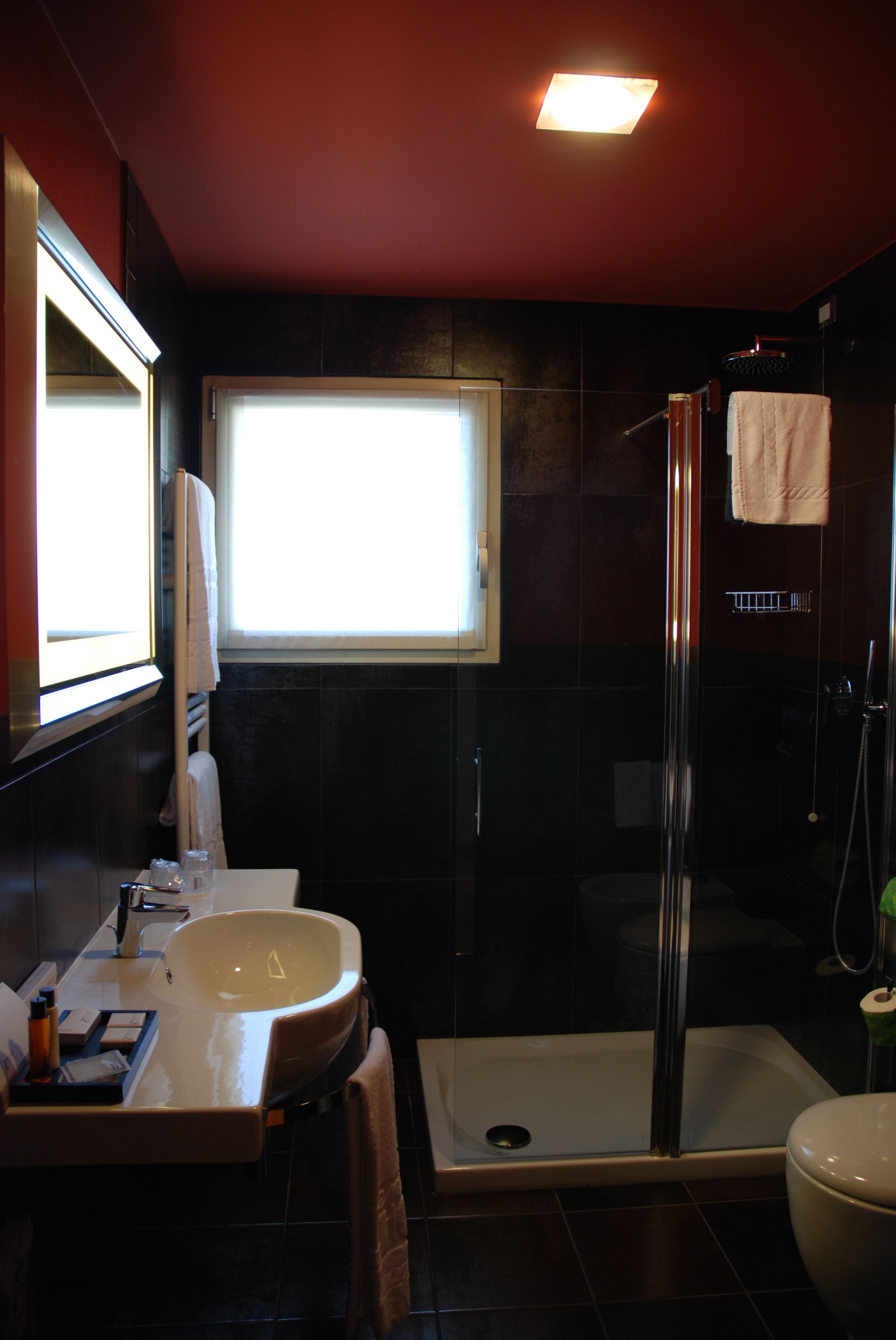 Een moderne badkamer met een glazen douchecabine, een groot wastafelmeubel en een toilet.