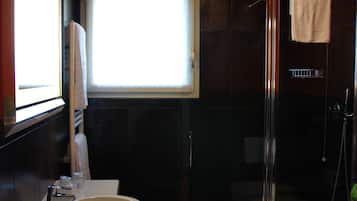 Een moderne badkamer met een glazen douchecabine, een groot wastafelmeubel en een toilet.